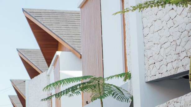 Un bâtiment moderne avec une façade en pierre, des éléments décoratifs en bois et des plantes vertes.