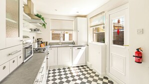 A kitchen with white cabinets, a black and white checkered floor, a dishwasher, and a fire extinguisher mounted on the wall. - Cherry Tree House - North East Escapes (Amble)