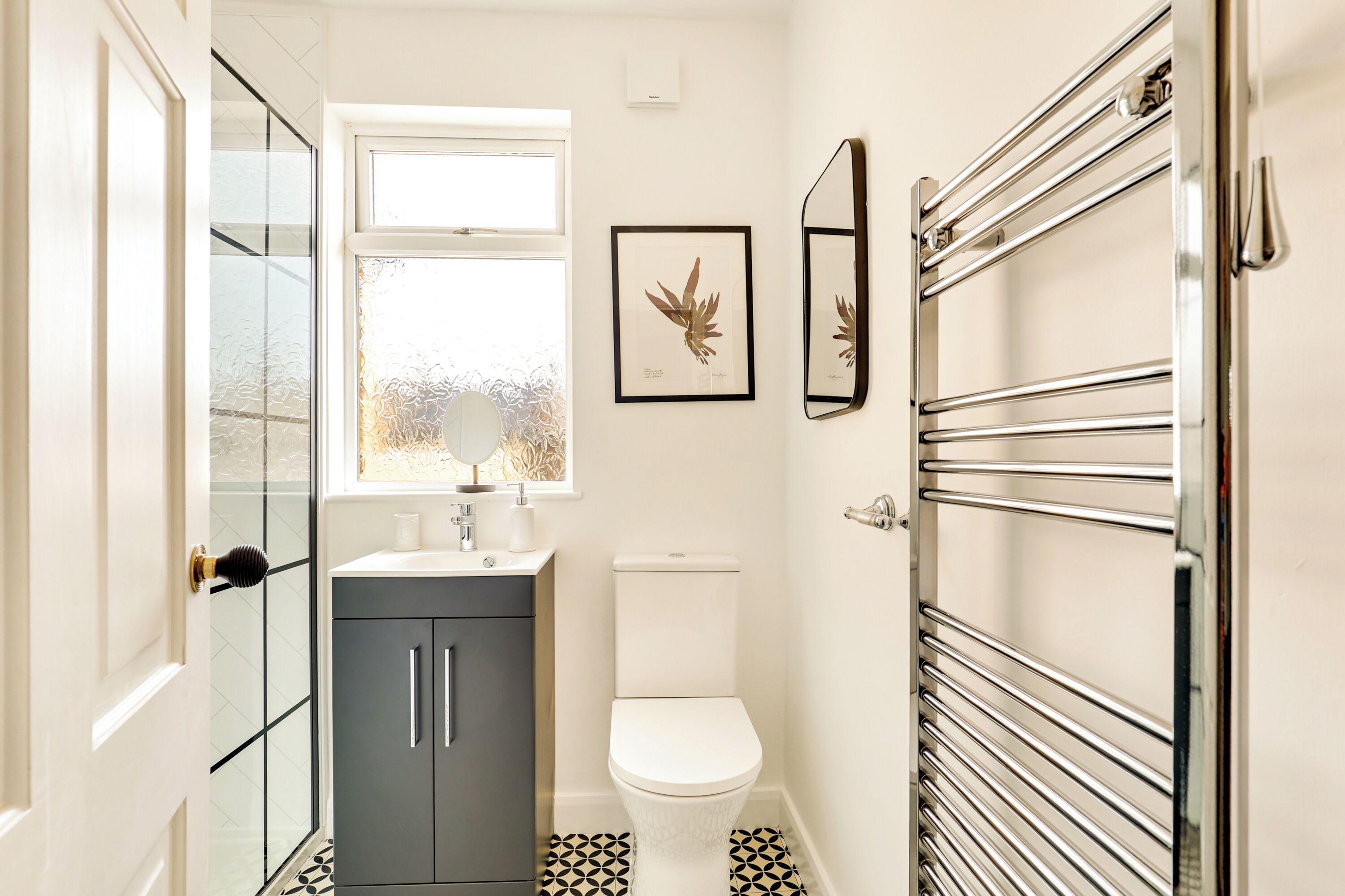 A bathroom with a toilet, a sink, a mirror, and a towel rack.