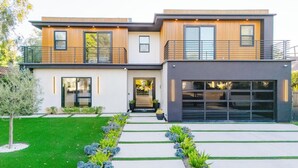 Ein modernes, zweistöckiges Haus mit Garage, überdachter Veranda und gepflegtem Rasen.