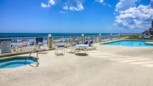 A pool area with lounge chairs and a view of the ocean. - Three Bedroom, Oceanfront Condo with a Pool (Murrells Inlet)