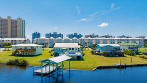 Un puerto deportivo con barcos amarrados, una piscina y una fila de casas de playa con balcones.