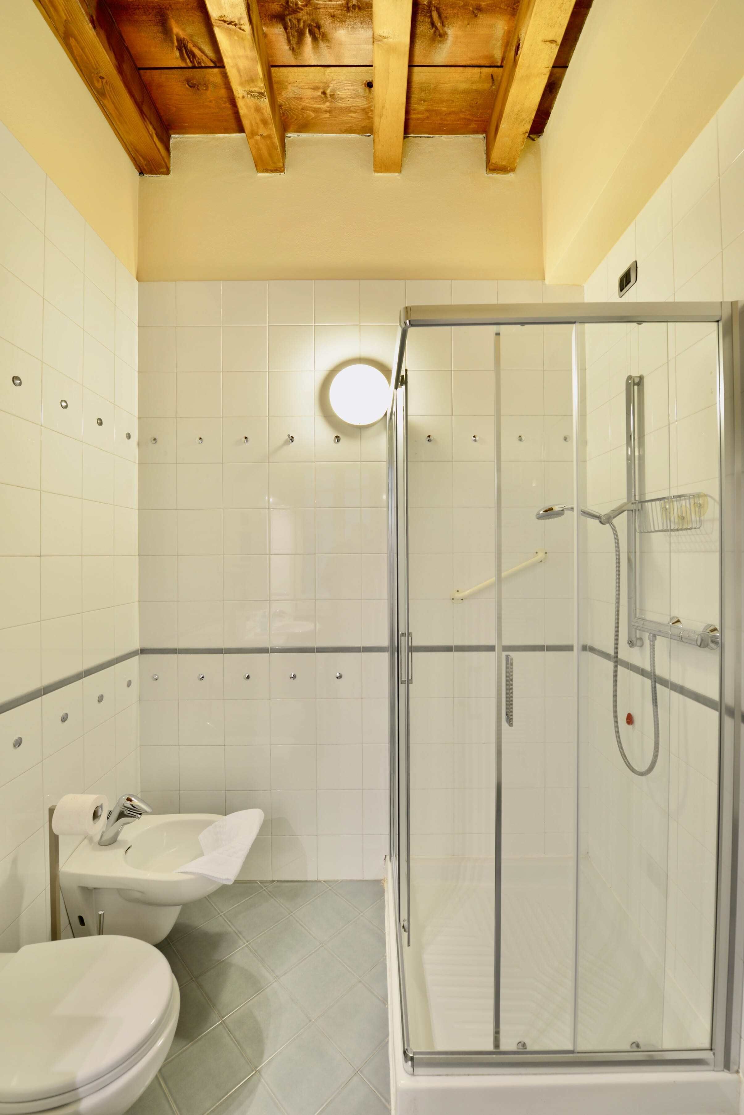 Un bagno con box doccia in vetro, lavabo e WC.