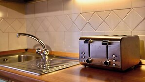 Une cuisine dotée d’un évier en acier inoxydable, d’un grille-pain moderne et d’un pare-feu géométrique.