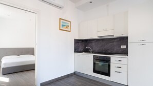 Una cocina moderna con armarios blancos, encimera negra y horno integrado.