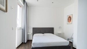 Un dormitorio moderno con una cama grande, una mesita de noche y un ventanal con cortinas.
