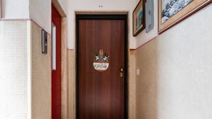 Un pasillo con una puerta de madera, un marco de puerta rojo y un cartel de bienvenida.
