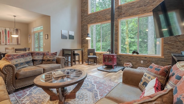 Una sala de estar acogedora con chimenea, ventanas amplias y decoración rústica.