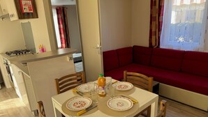 Una cocina compacta con refrigerador, estufa y un pequeño comedor con mesa para dos.