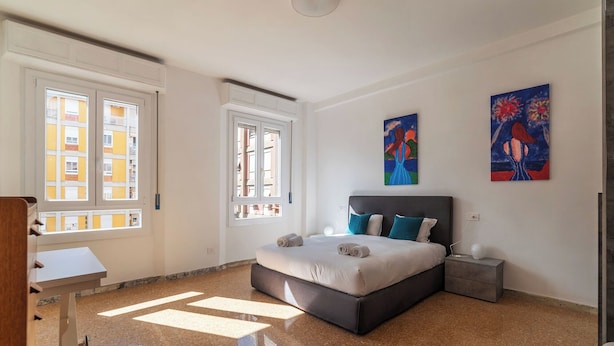 A bedroom with a large bed, two windows, and artwork on the walls. - Spacious flat near to Central Rome (Rome)