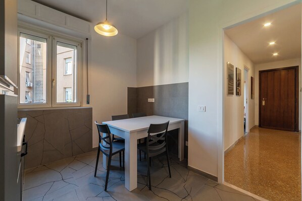 A modern kitchen with a white countertop, two black chairs, and a pendant light. - Spacious flat near to Central Rome (Rome)