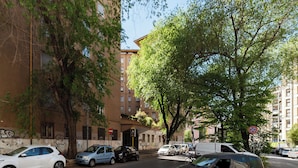 A street view with parked cars, a building with graffiti, and a tree. - Spacious flat near to Central Rome (Rome)