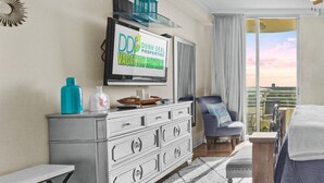 Een slaapkamer met een bed, een dressoir, een televisie en een balkon met uitzicht.