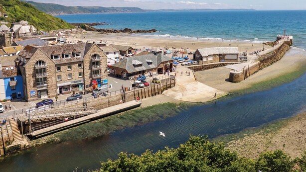 Un pueblo costero con edificios de piedra, una playa y un muelle.