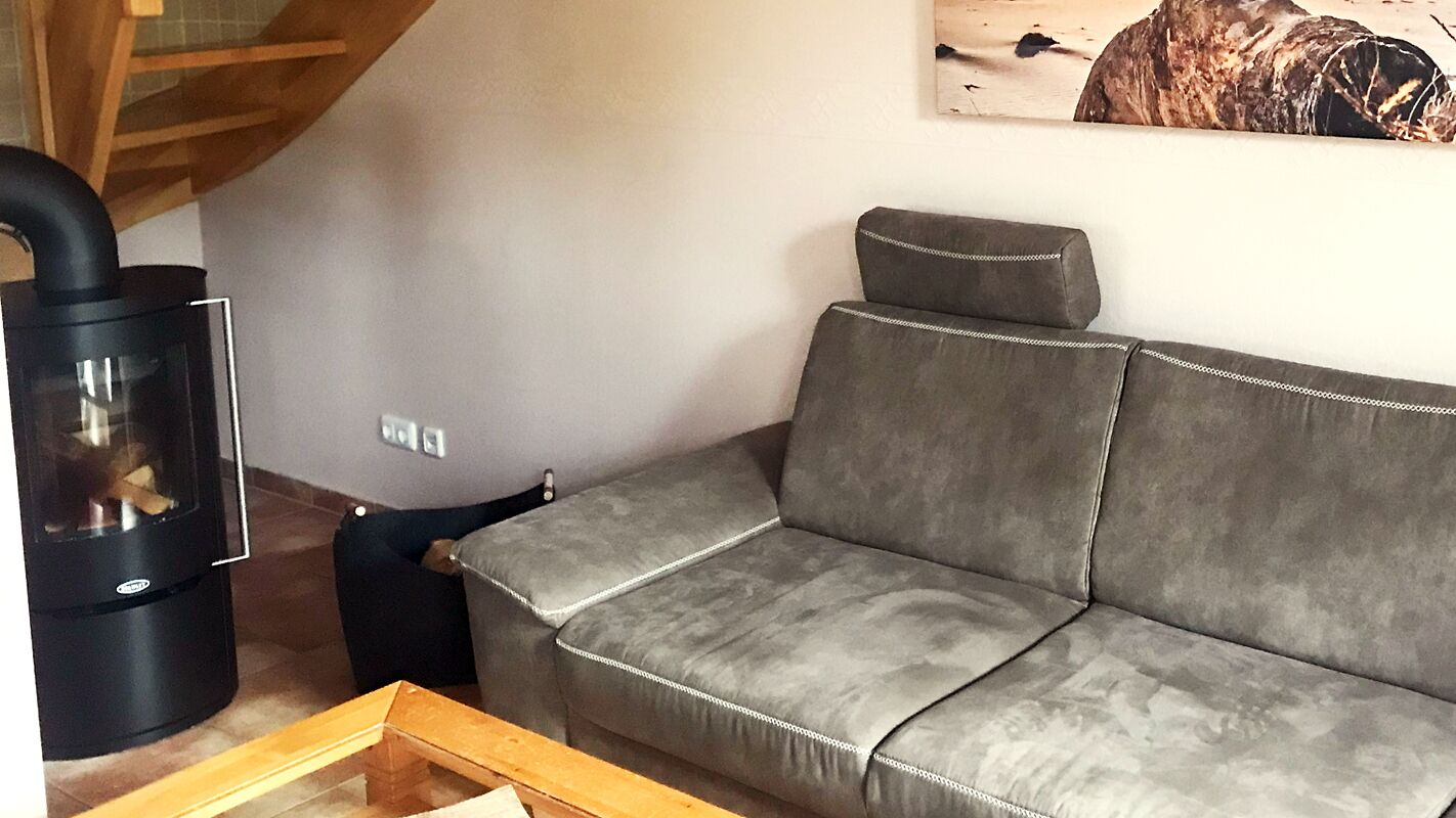 A living room with a gray sofa, a black wood stove, and a wooden table.