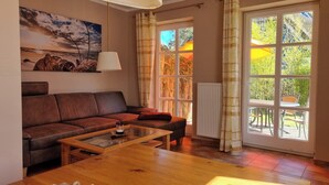 Un salon avec un canapé marron, une table basse en verre et un tableau accroché au mur.