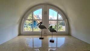 Une pièce dotée d’une grande fenêtre en arc et de deux sculptures d’oiseaux posées sur des piédestaux.
