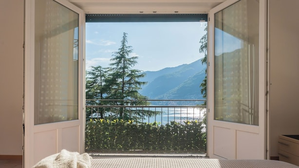 A bedroom with a large window offering a view of a mountain and a lake.