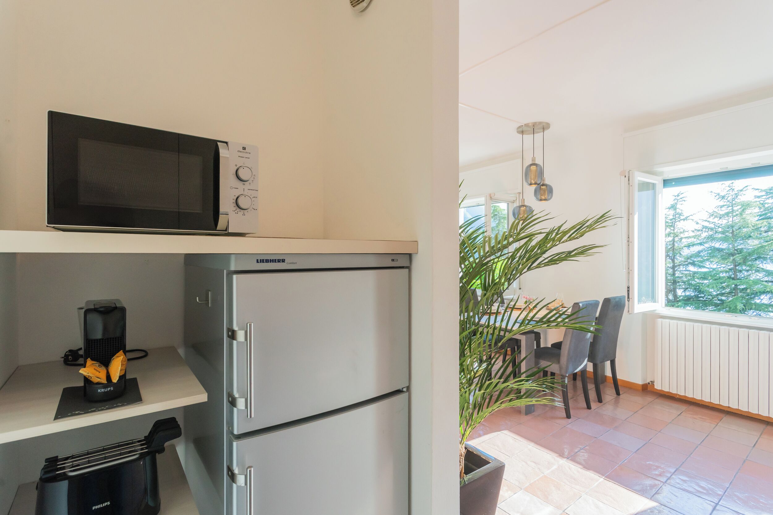 A compact kitchen with a microwave, a refrigerator, and a coffee maker on the counter.