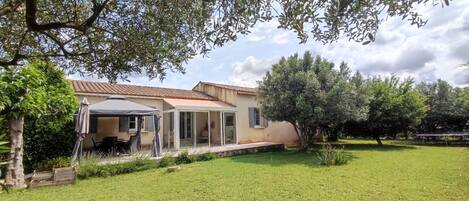 Una casa con patio, zona relax coperta e prato.