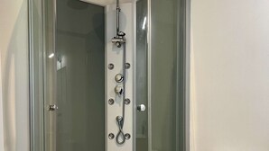 Un baño moderno con ducha de vidrio, inodoro blanco y piso de baldosas.