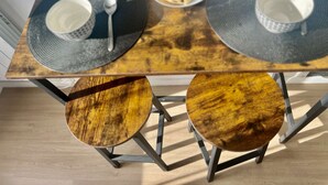 Una mesa de comedor con dos mesitas redondas de madera, un plato de pasteles y dos tazones con cucharas.