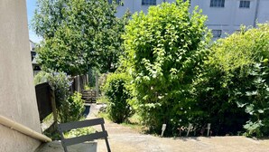 Un patio con una mesa azul y dos sillas azules, un florero y una planta en maceta.