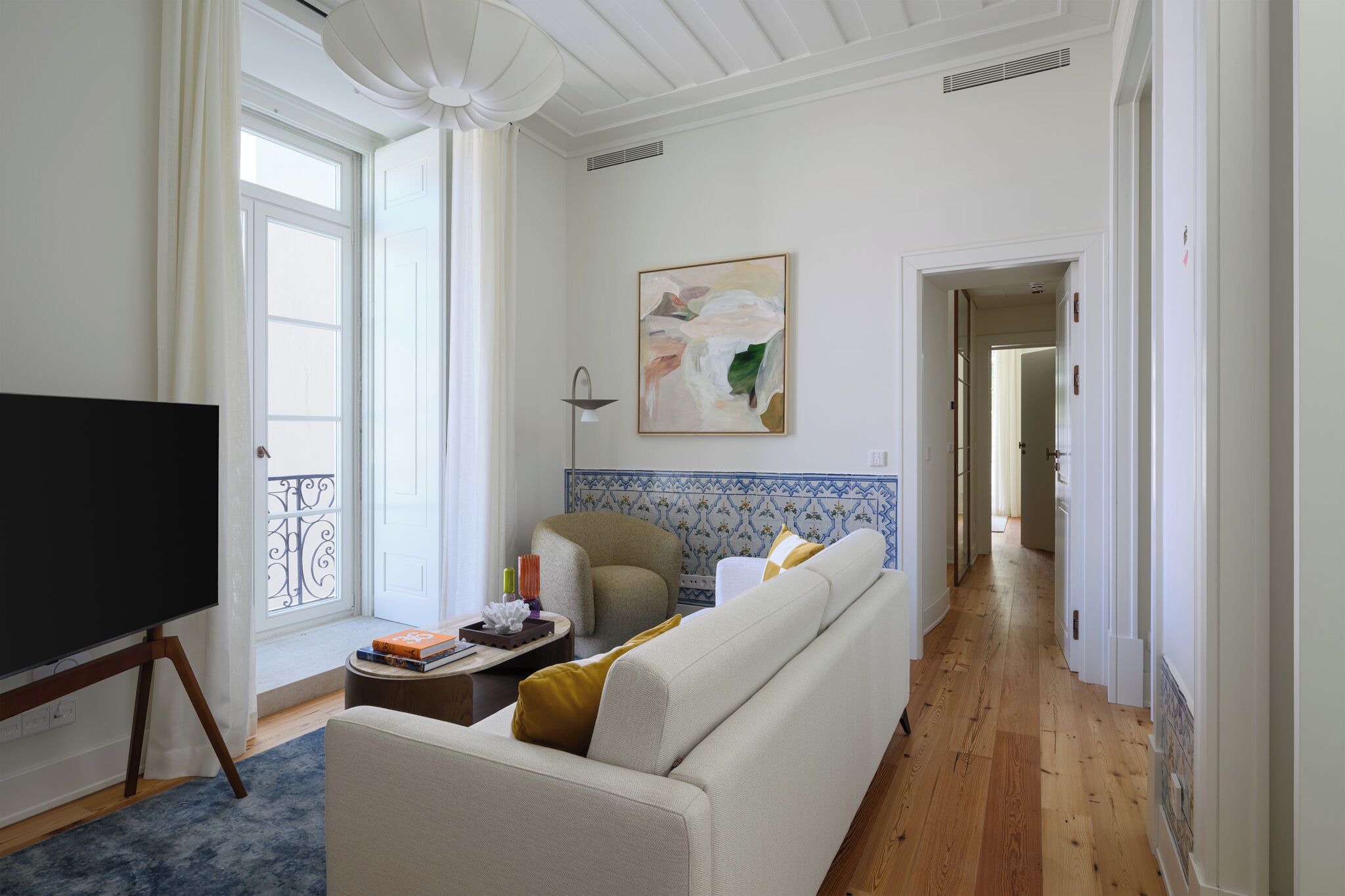A living room with a sofa, a television, and a window with curtains.