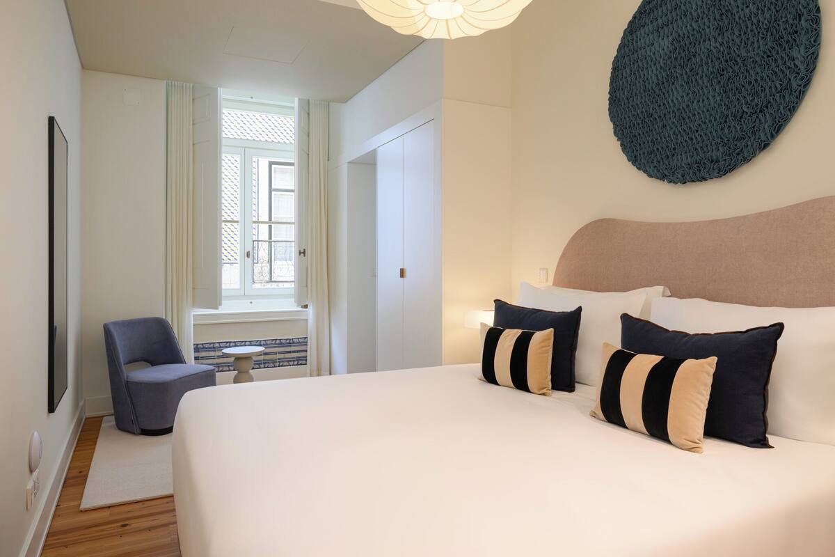Een hotelkamer met een groot bed, een stoel, een ronde wanddecoratie en een raam met gordijnen.