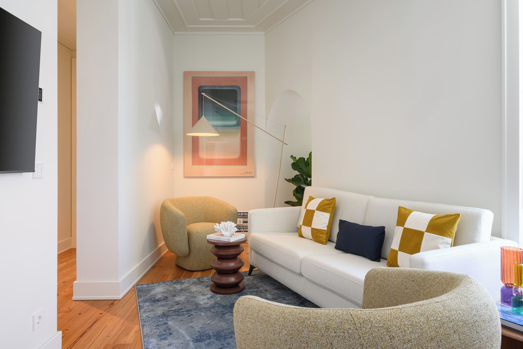 Una sala de estar moderna con un sofá blanco, una mesa de centro redonda y una planta grande.