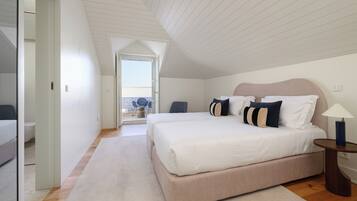 Een slaapkamer met een groot bed, een nachtkastje, een stoel en uitzicht op het balkon.