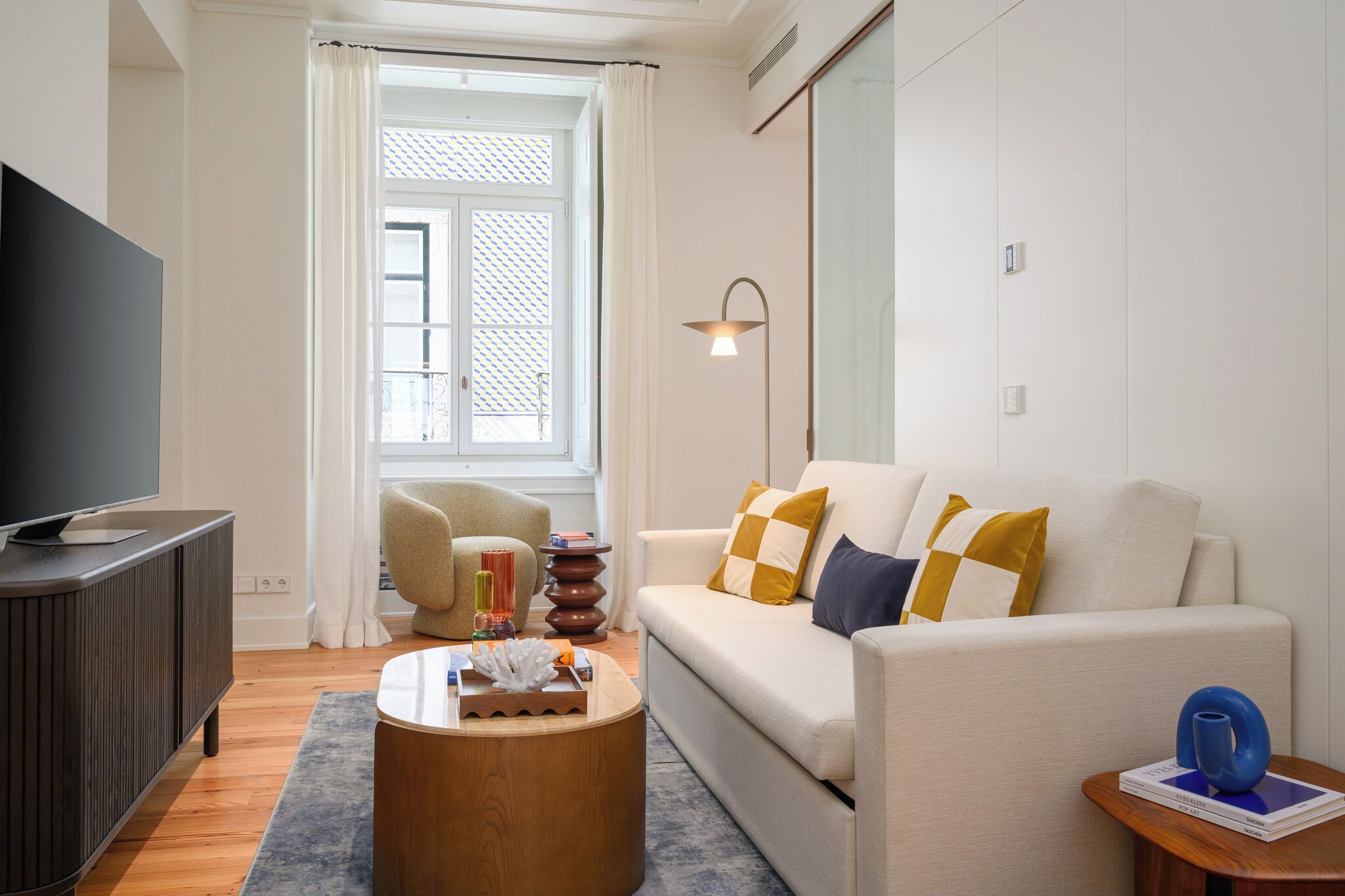 A modern living room with a sofa, a coffee table, a TV, and a lamp.