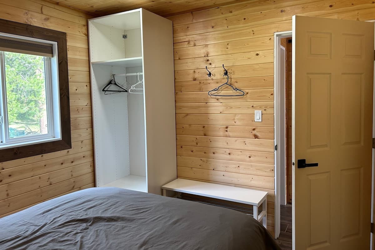 A bedroom with a bed, a wardrobe, a bench, and a door.