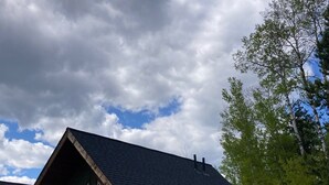 A single-story building with a dark roof, a front door, and a small porch area. There are two windows on the front wall and an air conditioning unit mounted on the exterior wall. - Cougar Mountain Lodge & Resort Ltd. (Valemount)