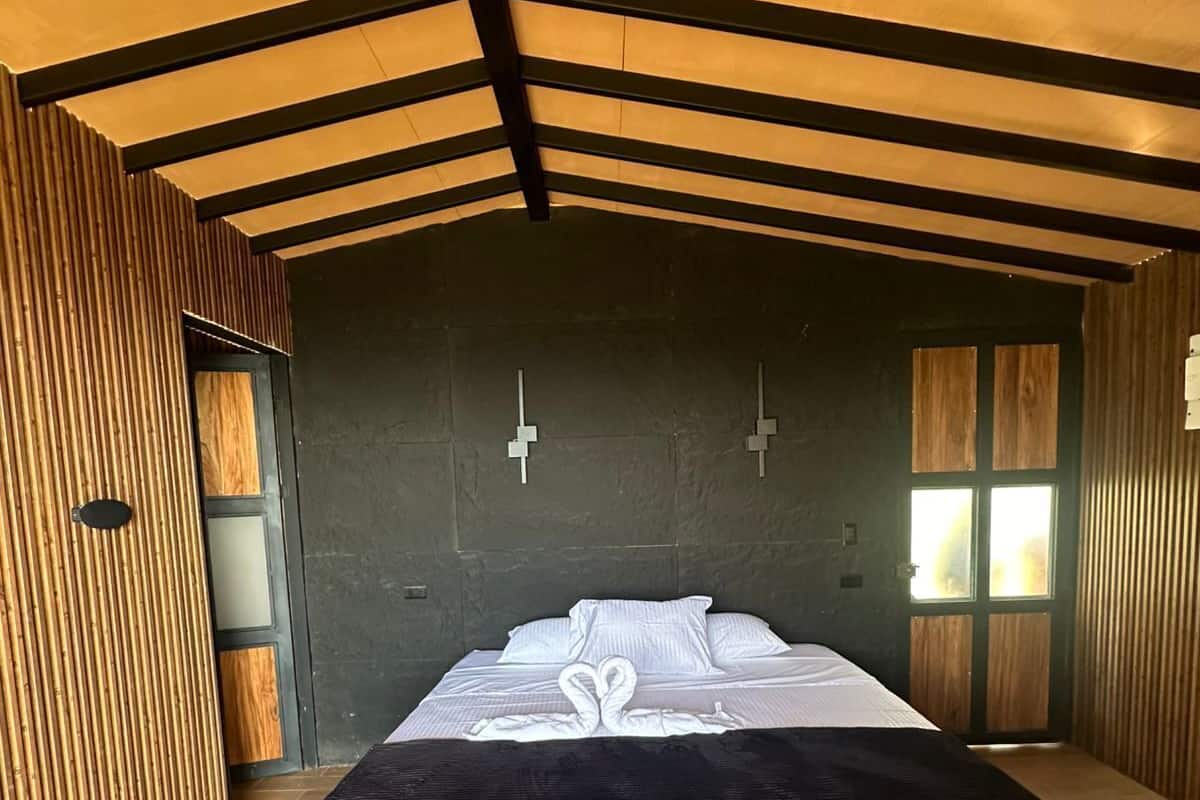 Un dormitorio moderno con una cama grande, paredes de madera y techo inclinado.