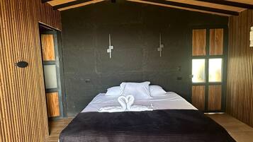 Un dormitorio moderno con una cama grande, paredes de madera y techo inclinado.