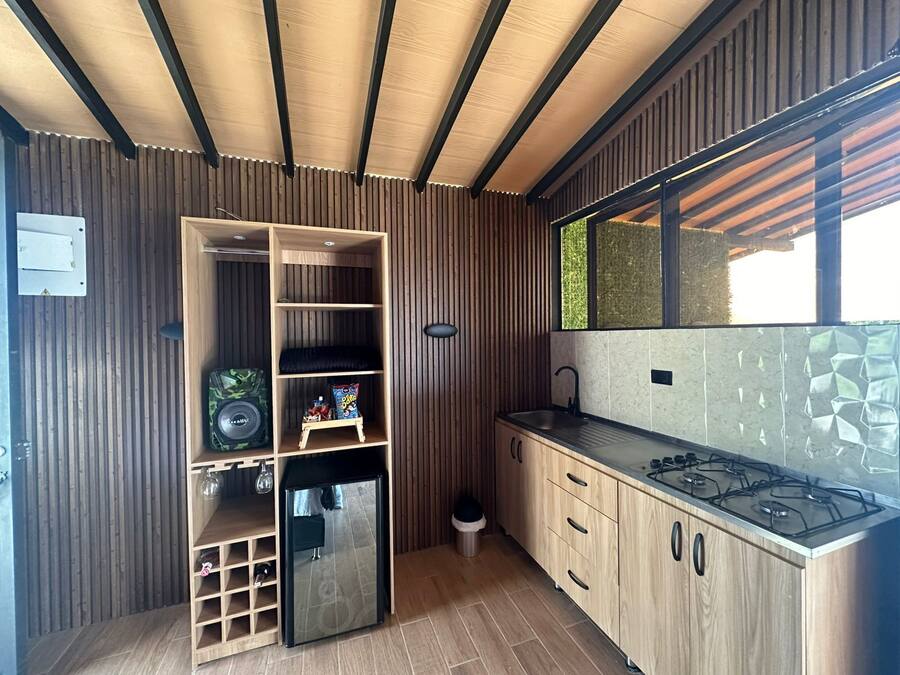 Una cocina compacta con refrigerador integrado, armarios de madera, estufa a gas y ventana que proporciona luz natural.