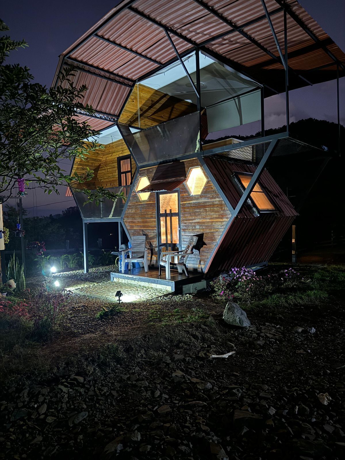 A modern, geometric house with a unique, angular design, featuring multiple levels and a covered outdoor area.