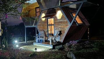 A modern, geometric house with a unique, angular design, featuring multiple levels and a covered outdoor area.