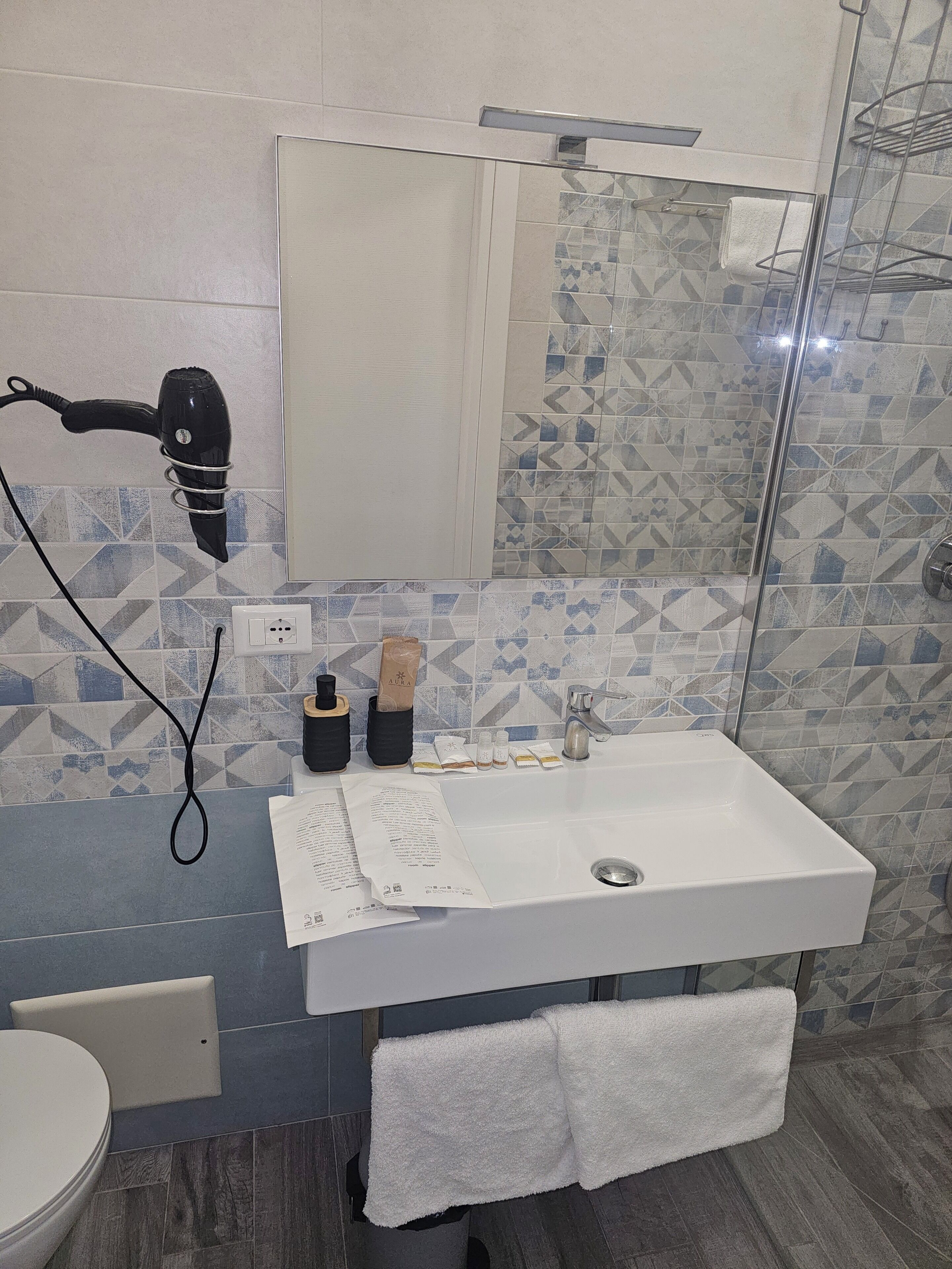 A bathroom with a white sink, a mirror, a hairdryer, and a towel rack.