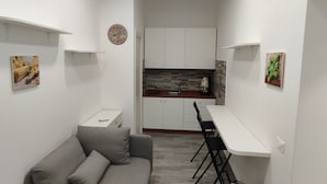A compact living space with a kitchenette, a sofa, a dining table, and a suitcase. - b&b Il Regno delle due Sicilie (Naples)