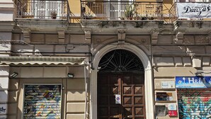 A building with a large arched entrance, a colorful door, and a sign for H&M. - b&b Il Regno delle due Sicilie (Naples)
