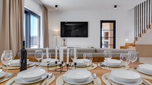A dining area with a table set for six, a bottle of wine, and candles.
