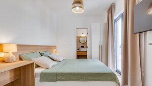 A bedroom with a bed, bedside table, lamp, and a TV mounted on the wall.