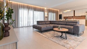 Een moderne woonkamer met een hoekbank, een salontafel en een keuken op de achtergrond.