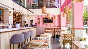Un restaurant doté d’un bar, de murs à rayures et de luminaires suspendus en osier.