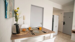 Un coin repas avec une table en bois mise pour deux personnes, un vase rempli de fleurs jaunes et une chaise blanche.