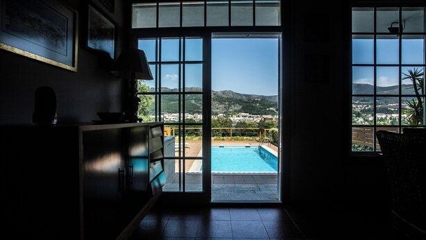 A room with a view of a swimming pool and mountains.