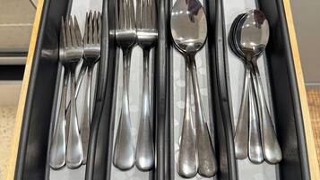 A drawer with a black interior containing various silverware items.