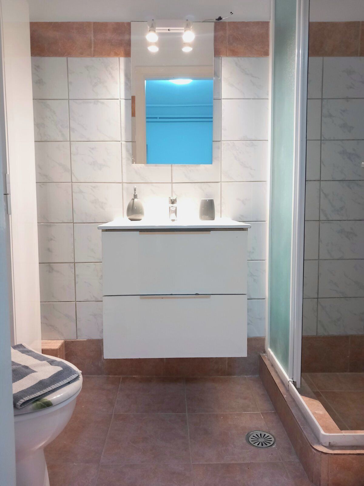 A bathroom with a white vanity, a mirror, and a shower area.